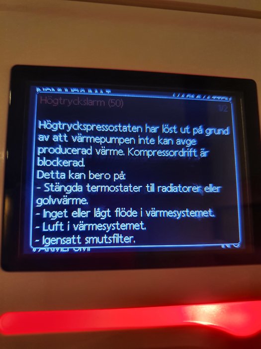 Display på en värmepump visar ett högtryckslarm med förklarande text om potentiella orsaker till felmeddelandet.