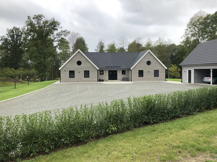 Två fristående carportar med stora lagringsutrymmen ovanpå, omgivna av en välskött gräsmatta och en grusuppfart.