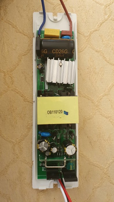 Inre delen av en elektronisk enhet med kondensatorer, anslutningstrådar och kretskort på en väggyta.