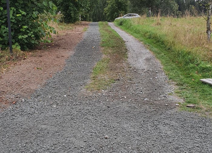 Nygrävd kabelsträcka för fiber längs en grusväg med omgivande grönska.