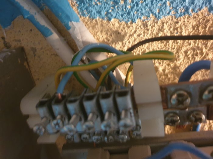 Elcentral med blå, brun och svart tråd inkopplade i säkringar, felaktig trådfärgning och potentiell säkerhetsrisk.