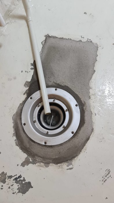 Nyinstallerad justerbar kvadratisk duschbrunn i ett pannrum med omålade betongytor runtomkring.