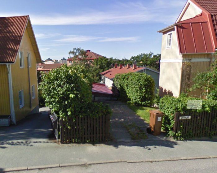 Google Streetview-bild av ett gathörn med två gula hus, grön häck och grusinfart.