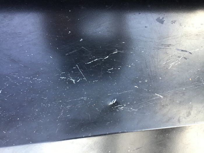 Närbild på en svart plåtyta med synliga repor och rispor som diskuteras i byggforumet.
