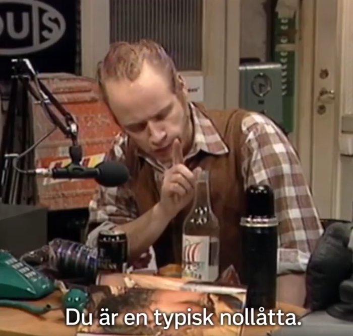 Man i skjorta gestikulerar med finger framför munnen vid radiomikrofon och termos. Text: "Du är en typisk nollåtta.