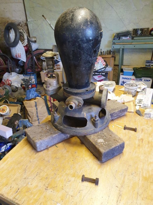 Gammal handpump från wisby mekaniska verkstad på ett arbetsbord i ett rörigt garage.