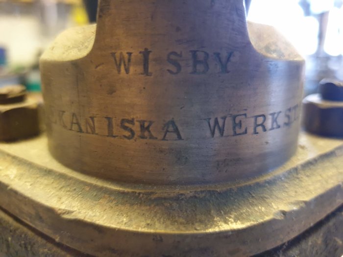 Närgränsad bild av en antik pump märkt med "WISBY MEKANISKA WERKSTAD" som indikerar dess ålder och ursprung.