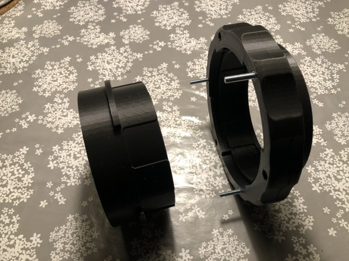 Fyra svarta 3D-utskrivna PLA-delar till koppling av spånsug och hyvel med en skruv för montering.