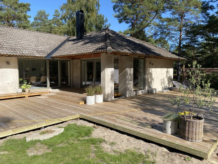 Trädäck under konstruktion vid hus med små detaljer och brädor som ska färdigställas.