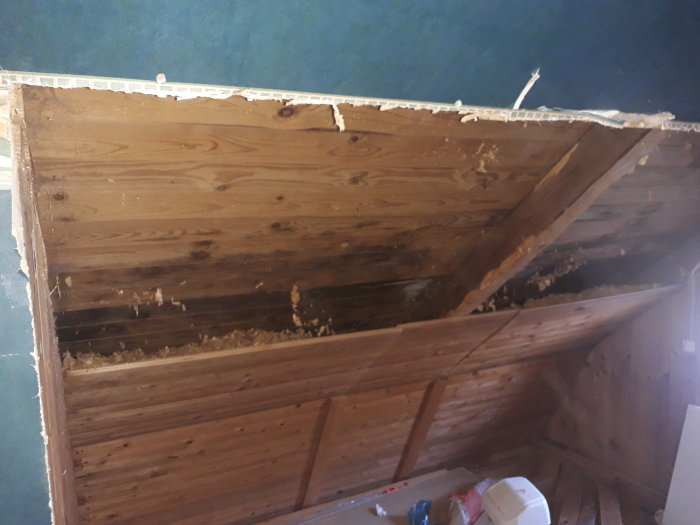 Snedtak med synliga takstolar och borttagen vägg, med isolering synlig i väggens övre del.