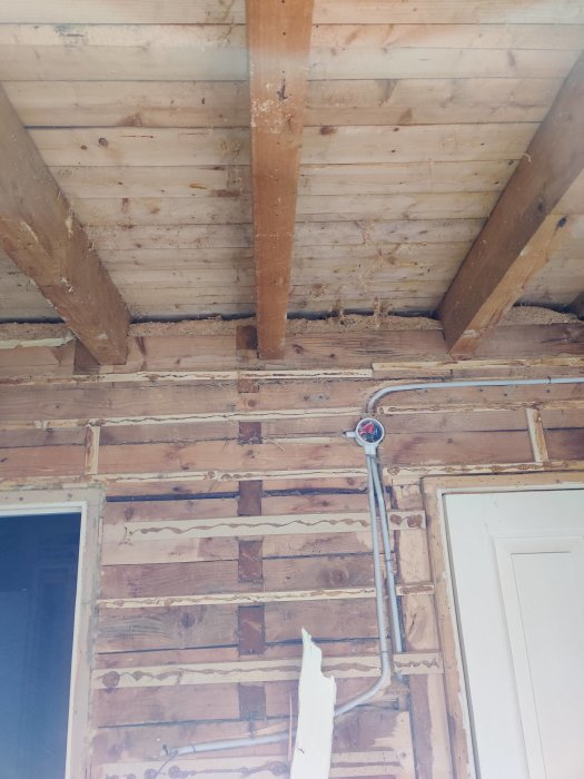 Renovering av hus från 1935 med exponerade bjälkar och rörledningar i ett öppet takbjälklag.