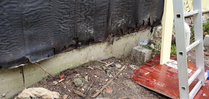 Sliten vindpapp på husvägg med skador och stege intill, behov av byte inför ny trappa.