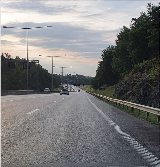 Bilar som kör i mittfil på en trefilig motorväg under en tidig morgon.