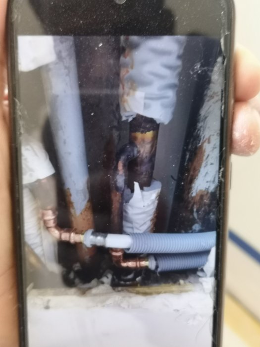 Vatten- och avloppsrör med förlängning, inklusive grått flexrör och kopparledningar, inne i en byggnadsstruktur.