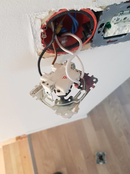 Osäkerad strömbrytare utan kåpa monterad i vägg vid trappa, synliga trådar och dosa.