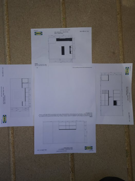 Fyra utskrivna IKEA köksplaneringsskisser utspridda på ett golv, med synliga mått och layouter.