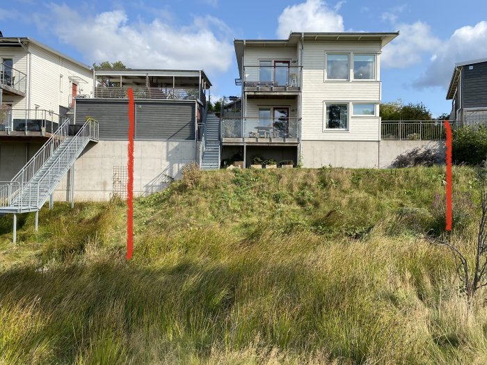 Översikt av slänt med markerade områden för potentiella stödmurar vid en tomtgräns.