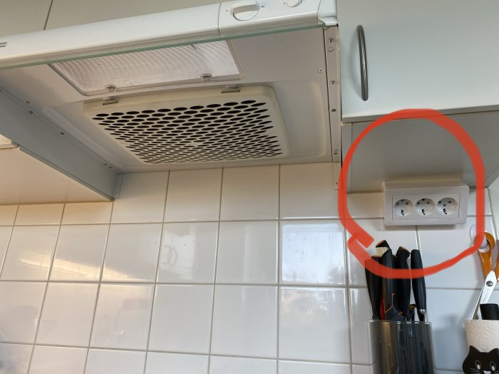 Kök med spisfläkt och markerat vägguttag ovanför bänk, indikerande förvirring kring el-gruppering.