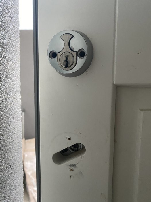 Cylinderlåshuvud på en dörr utan synliga skruvar eller spärrtrycke.