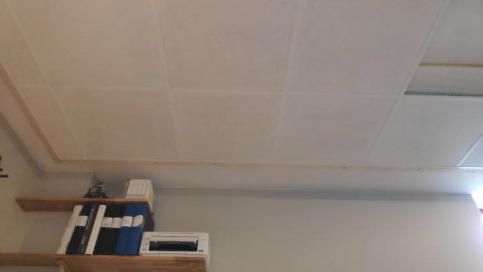 Utsikt av ett tak med jämna paneler ovanför en arbetsbänk med böcker och en skrivare.