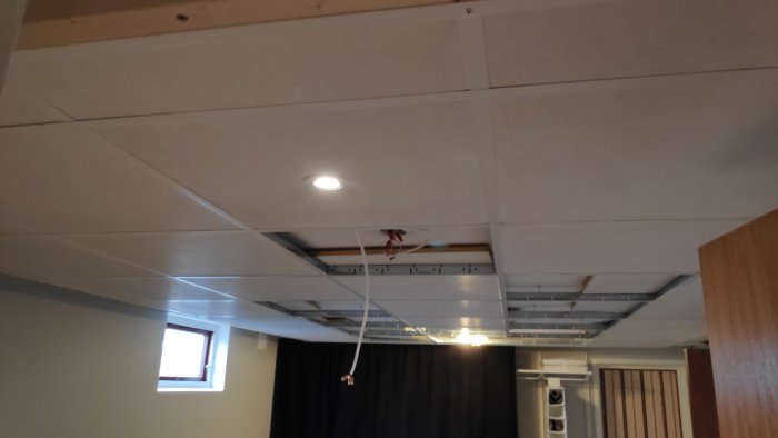 Undersida av ett tak med infälld belysning och oavslutad installation, synligt regelverk och kablage.