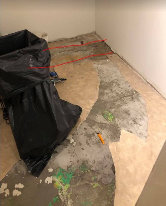 Betonggolv med limrester och röd linje markerar avloppsrörets löpning, synliga fuktskador där röret ligger.