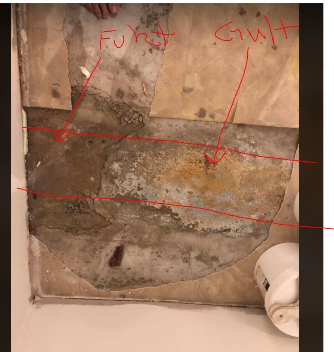 Fuktigt betonggolv med gulaktiga fläckar och röda linjer som markerar avloppsrörets sträckning.