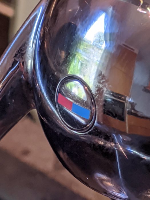 Närbild av en kromad blandare med en liten synlig logotyp och återspeglingar.