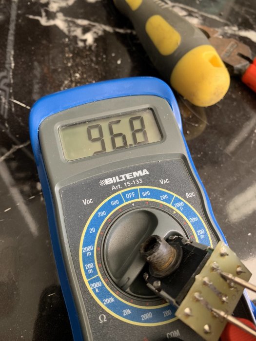 Multimeter visar 96.8 ohm, nära 200k inställning, med verktyg i bakgrunden.