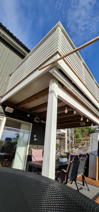 Nyinstallerade vita underhållsfria paneler på takutsprånget på en uteplats med utsikt mot en klarblå himmel.