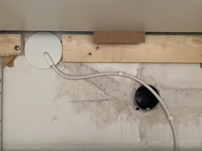 Nyinstallerad eldosa med kablar på en vägg med trästöd och välorganiserad kabelföring.