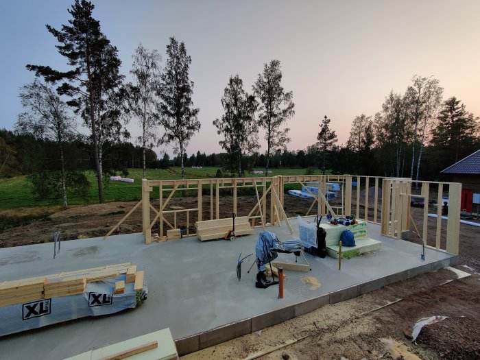 Grund till hus med tre nybyggda träväggar under skymningen på landsbygden.