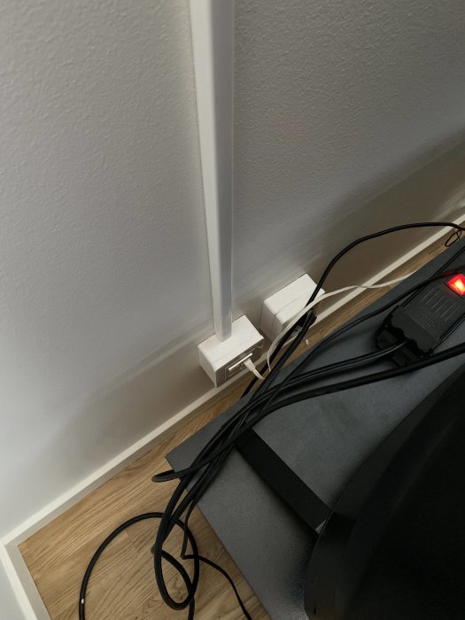 Ethernet-kablar anslutna till vägguttag vid golvlist, med fler sladdar och strömförsörjning.