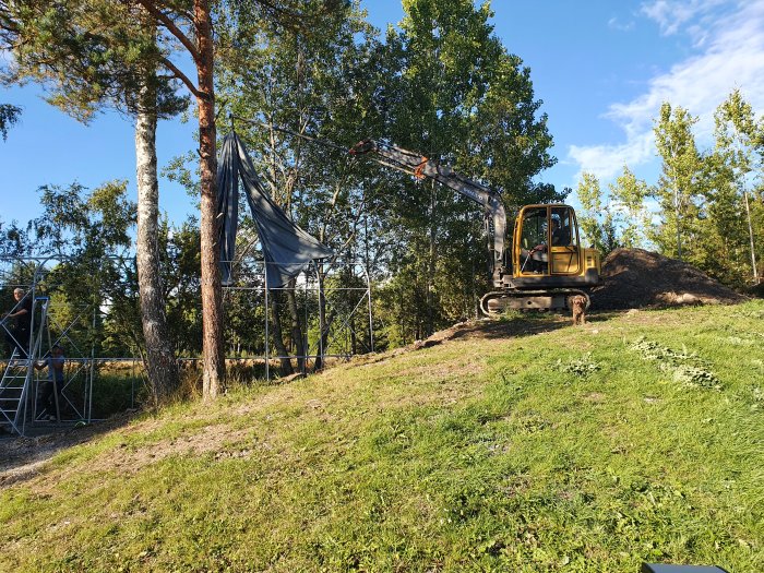 Byggarbetsplats utomhus med tältkonstruktion, grävmaskin och hund.