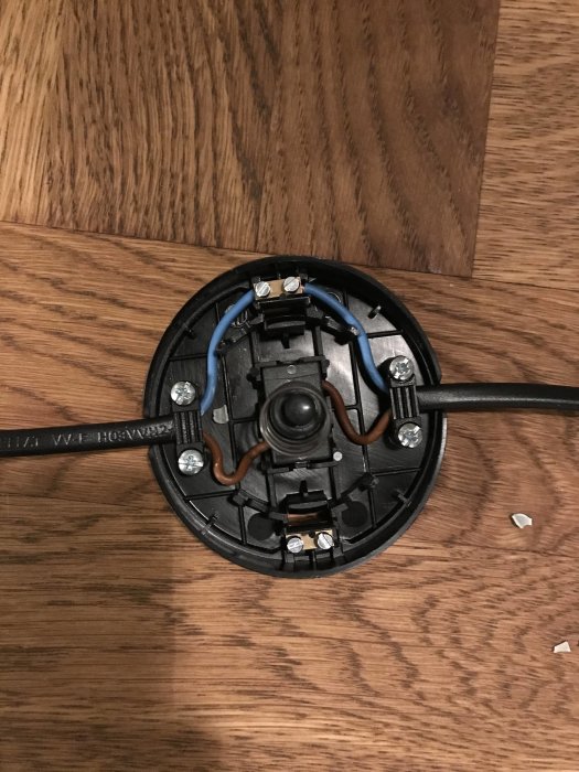 Installationsvy av elektriska komponenter i en golvlampa på trägolv.