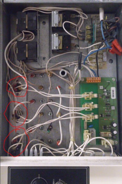 Översikt av en elektrisk apparats insida med tre triac-komponenter markerade med röda cirklar, omgivna av kablar och kretskort.