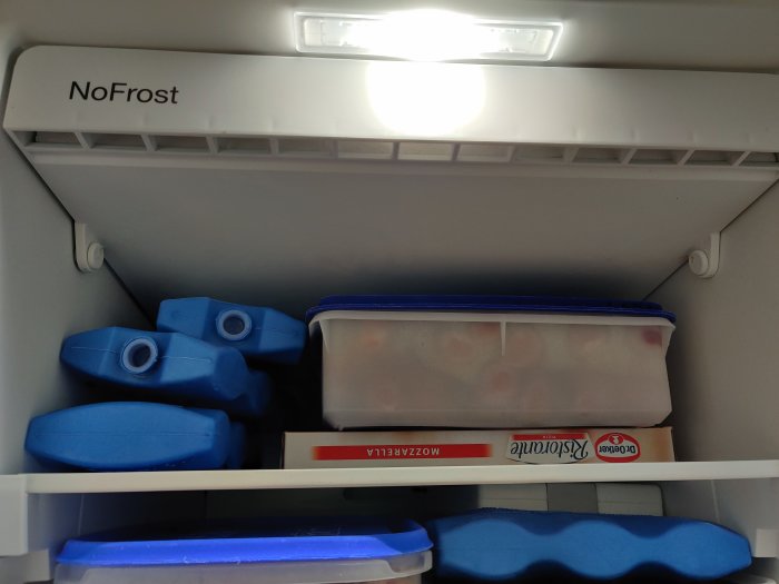 Inre övre delen av en Bosch-frys med NoFrost-loggan, plastkåpa, kylklampar och förpackningar.