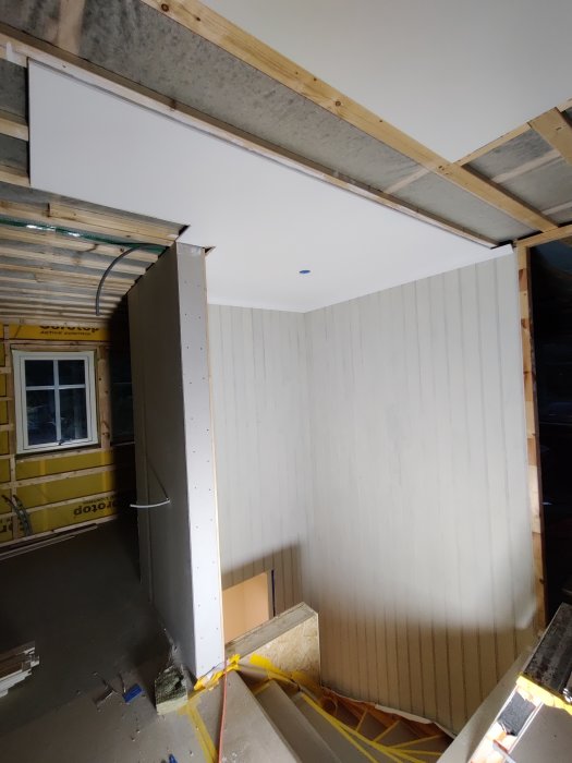 Nymålat vitt tak och pärlspont i en trappuppgång under renovering.