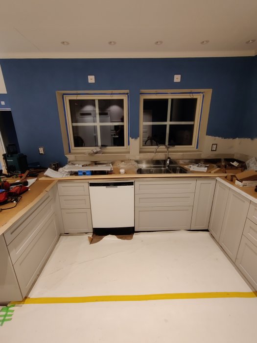 Köksrenovering med omonterade lådor och handtag, blå väggar, ej färdigställd inredning.