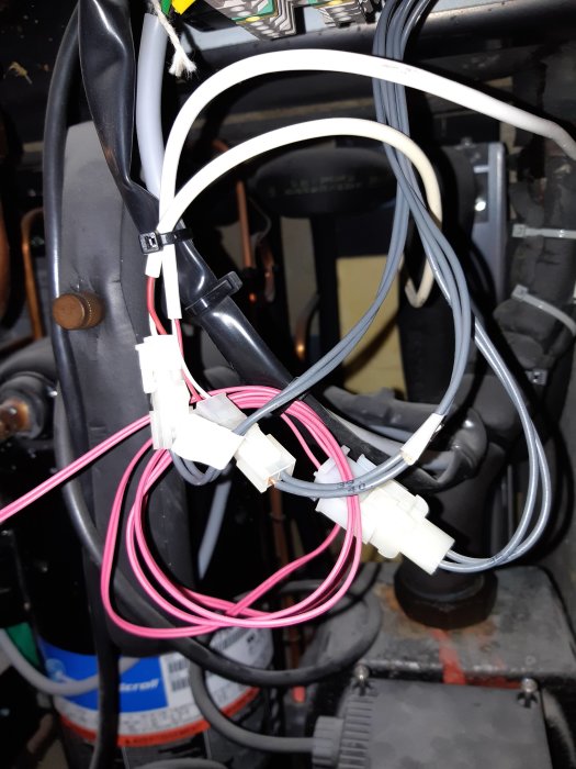 Elektriska kablar och kontakter inuti en värmepump med synlig skada på isolering.