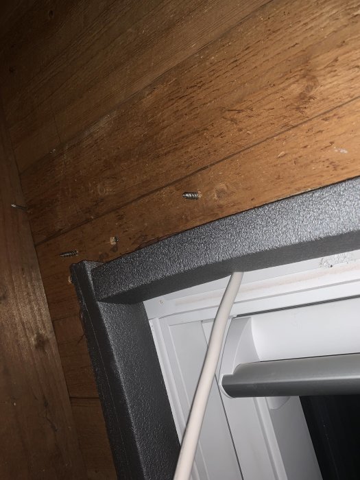 Elkabel hänger löst från ett nyligen installerat Velux takfönster mot träpaneltak.