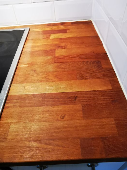 Träköksbräda med områden som tappat lyster nära spisen, resten visar rikare färg och bättre skick.