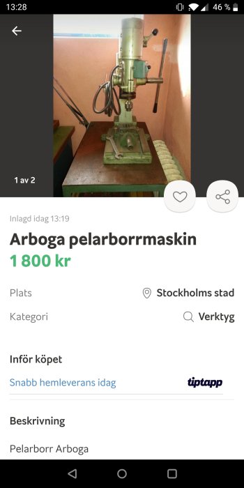 Grön Arboga pelarborrmaskin står på en arbetsbänk, otydlig bakgrund, säljes för 1800 kronor.