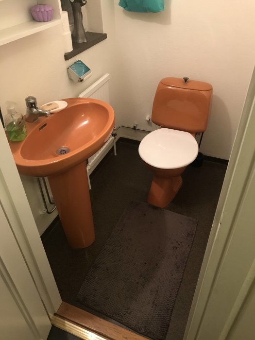 Äldre toalett och handfat i orange färgton redo för renovering, till salu från Eskilstuna.