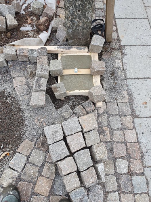 Nylagd betong för postlådefundament och tröskel vid smågatstenskant.