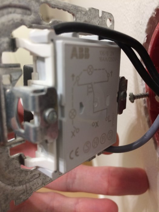Närbild av en ABB Impressivo strömbrytare delvis monterad i vägg med synliga kablar och skruvar.