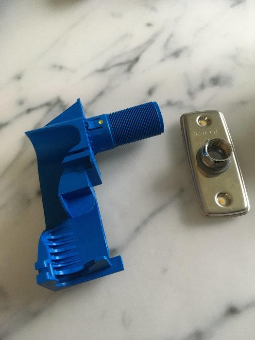 Blå Vattete bockfixtur och metall väggbricka på marmorbakgrund, avsedda för vatteninstallation.
