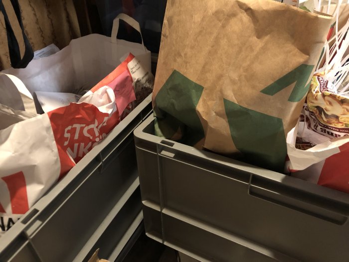 Plastback fylld med återanvända papperskassar och plastpåsar för återvinning.