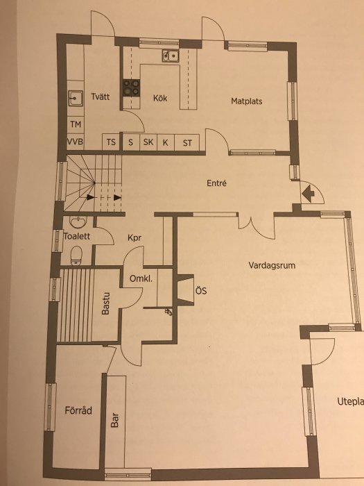 Planlösning av ett hus med markerade rum såsom kök, vardagsrum, bastu och toalett samt entré och uteplats.