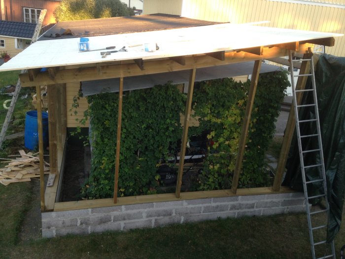 Nybyggd carport med takstolar och lecablock, avklätt tak, tryckimpregnerade reglar.